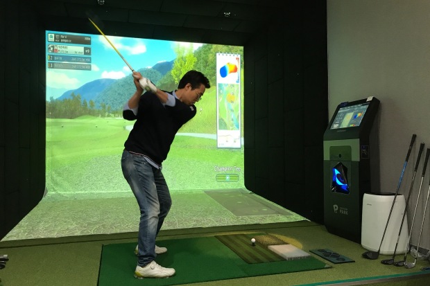 Kang Duck-hee, a 47-year-old insurance salesman, takes a swing during a round of screen golf with two colleagues in Seoul.